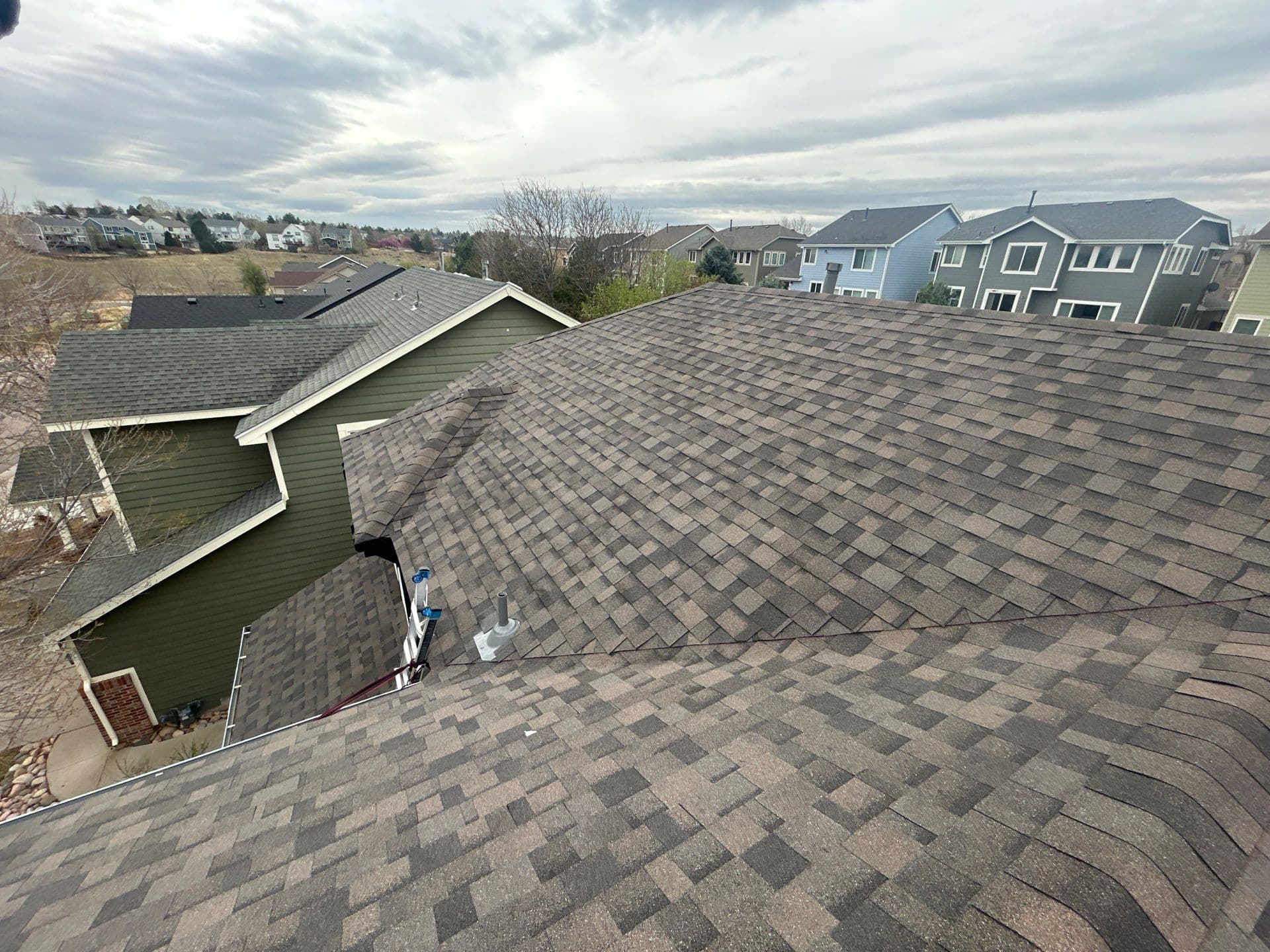 Large residential roof replacement with brown architectural shingles, aerial view of Colorado neighborhood