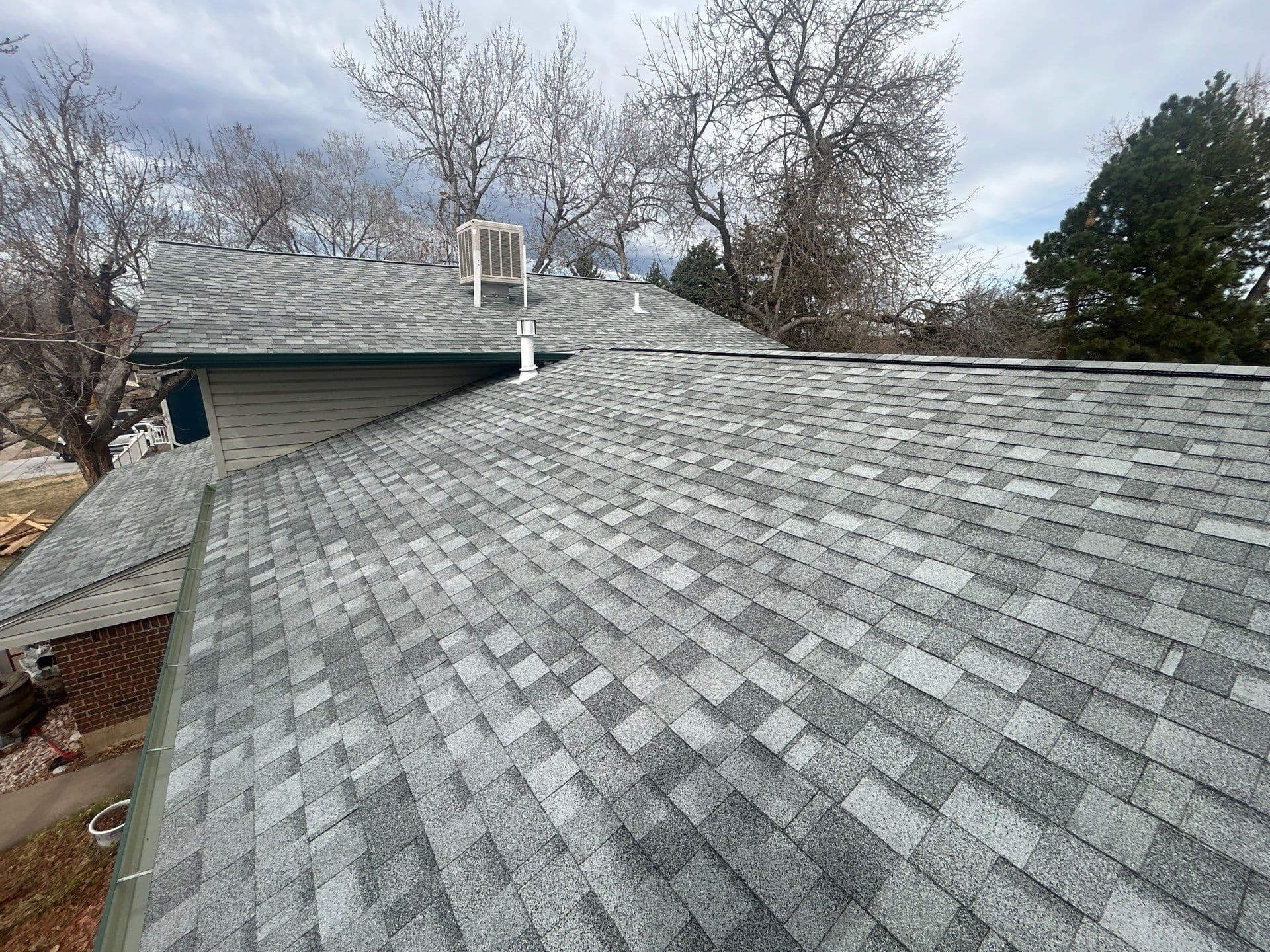 Multi-plane residential roof replacement with light gray architectural shingles and ridge ventilation, Denver Metro area