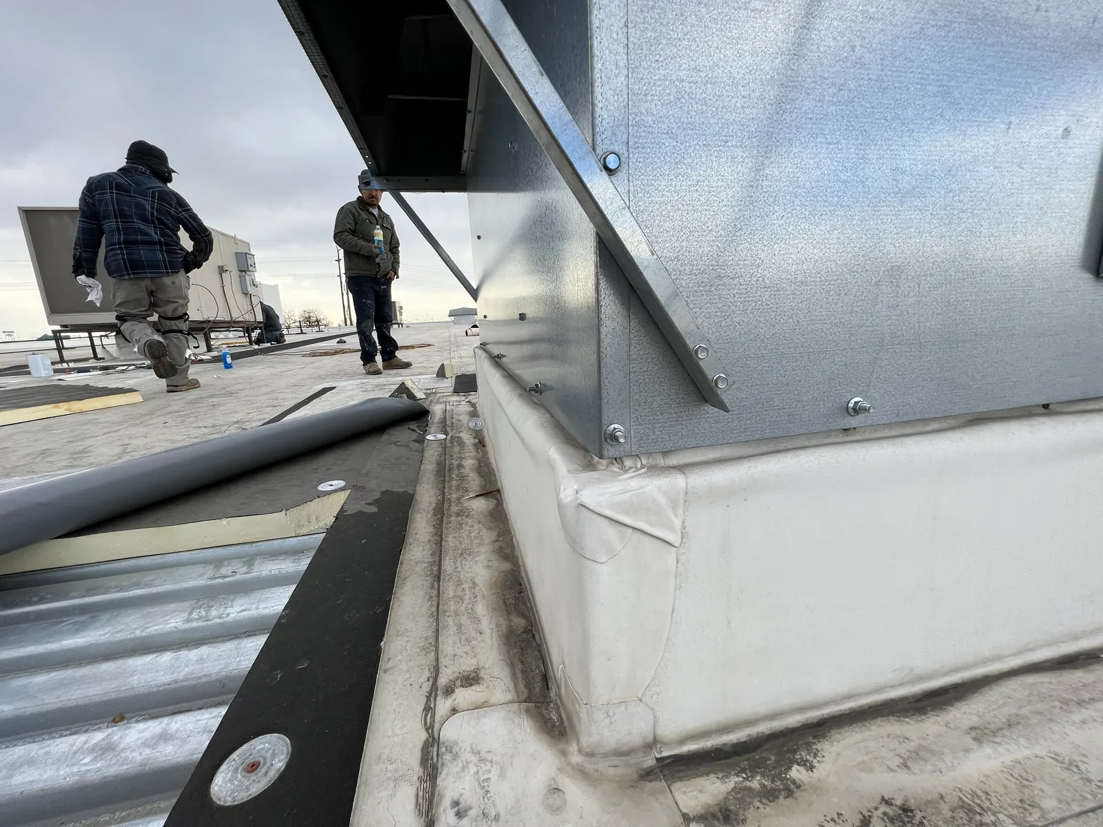 Gen 3 crew repairing flashing at a rooftop curb on a flat roof