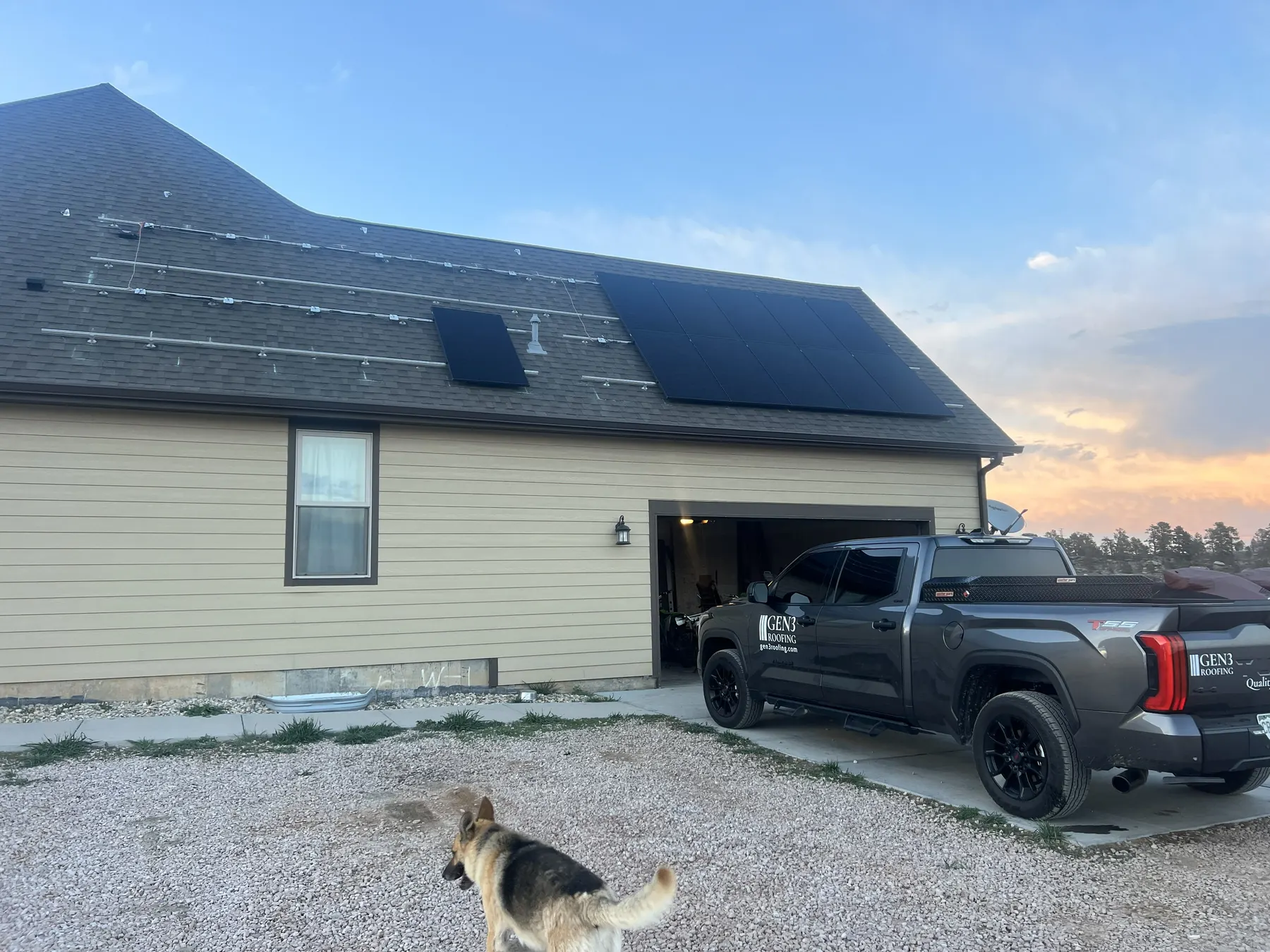 Two-story home with a dark roof and solar array, Gen 3 truck out front at dusk